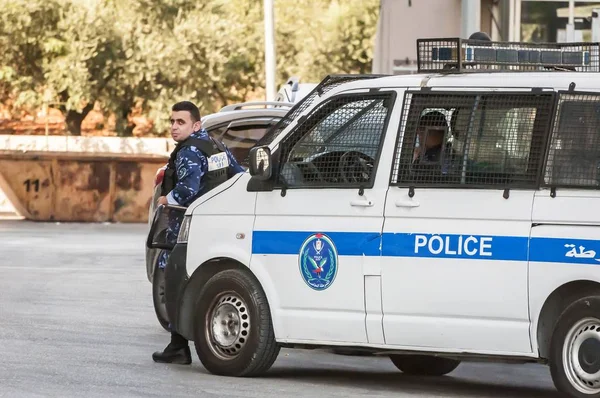 Ramallah, Filistin. 31 Ağustos 2019. Ramallah şehir merkezinde devriye arabasının yanında duran Filistinli polis memuru. Filistin güvenlik gücü kavramı imajı.