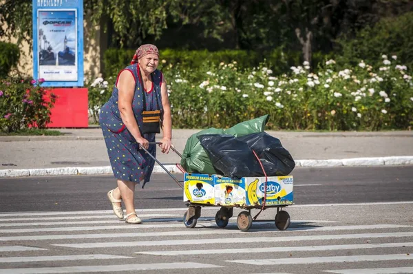 蒂拉斯波尔 德涅斯特河左岸 摩尔多瓦 2019年8月24日 在普里德内斯特罗维安 莫尔达维亚共和国首府蒂拉斯波尔市中心 穿着浅夏礼服的老妇人穿着一辆满载不明物品的推车过马路 — 图库照片