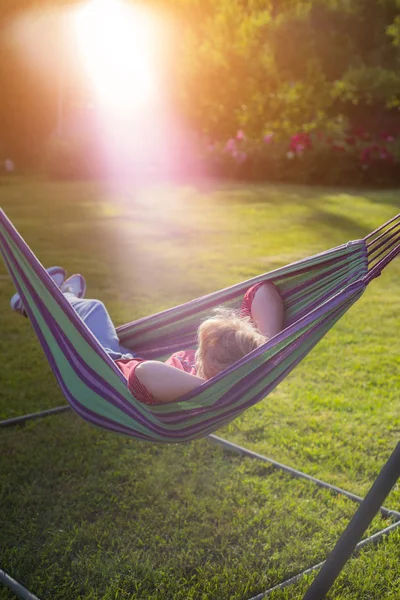 beautiful girl resting in a hammock at sunset.