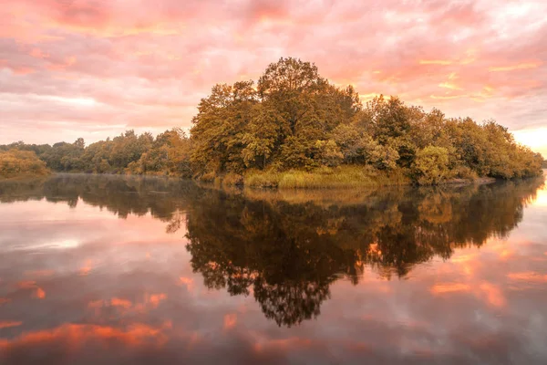Symmetry reflection on the autumn river. Sunrise