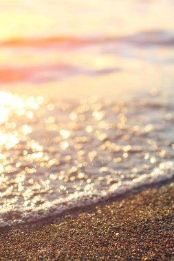 Sahilde ıslak deniz kumu arka planda güzel altın gün batımı. Gün batımında okyanus kıyısındaki deniz kumlarını kapatın. Gün batımında deniz manzarası. Sahilde gün batımında altın ıslak kum.