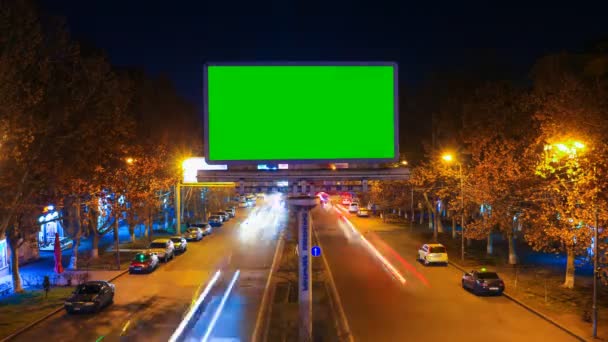 Μια πινακίδα με πράσινο chroma κλειδί με φόντο ένα τοπίο νύχτα πόλη γρήγορα κινούμενα αυτοκίνητα με μακρά έκθεση. 4 k Time Lapse βίντεο. — Αρχείο Βίντεο