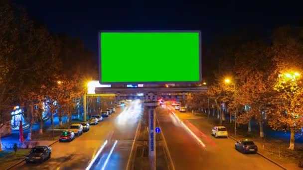 Μια πινακίδα με πράσινο chroma κλειδί με φόντο ένα τοπίο νύχτα πόλη γρήγορα κινούμενα αυτοκίνητα με μακρά έκθεση. Ώρα λήξη του βίντεο. Η κάμερα πλησιάζει. — Αρχείο Βίντεο
