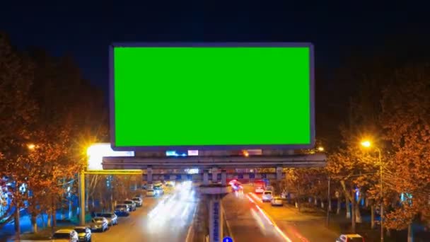 Un panneau d'affichage avec clé chromatique verte sur un fond de paysage nocturne de la ville de voitures en mouvement rapide avec une longue exposition. . — Video