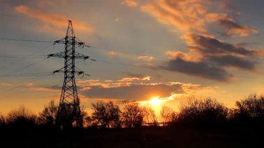 Zaman atlamalı video. Turuncu kırmızı renklerle güzel bir dramatik günbatımı arka plana karşı ağaçlar ile bir elektrikli kutup silüeti. Gün gece olur.