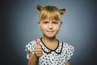 Gangsterlere gösteriş yapan mutlu kız. Gri üzerinde izole bir şekilde gülümseyen portre çocuğu.