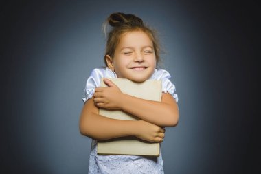 Gri arka plan üzerinde izole kitap gülümseyen yakışıklı küçük kız