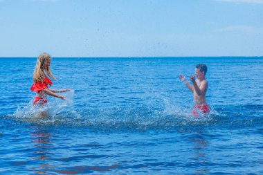 Çocuklar plajda dinlenir ve yazın denizde şiltelerde eğlenir ve top oynarlar..