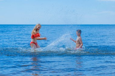 Çocuklar plajda dinlenir ve yazın denizde şiltelerde eğlenir ve top oynarlar..