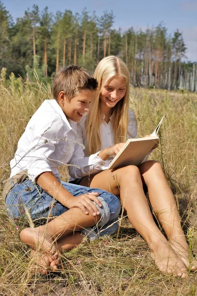 Ragazza e ragazzo in natura scolari leggere un libro in natura — Foto Stock