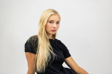 Güzel kız uzun saçlı beyaz arka planda oturur. Yakın plan..