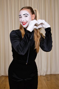 Gülen pandomimci kalpten bir hava mesajı gönderir. Tiyatro sahnesine yakın çekim.