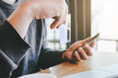Kredi kartı tutan ve kahve dükkanında - Online ödeme kavramı online alışveriş için dizüstü bilgisayar kullanarak insanın yakın çekim