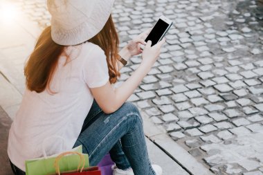 Mutlu cazibe Asyalı kadın alışveriş torbaları ile alışveriş merkezi Smartphone kullanarak