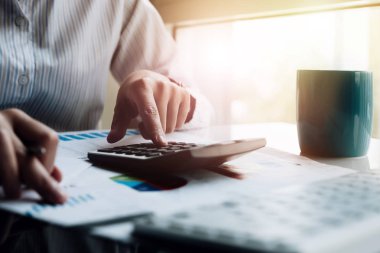 İş yeri verilerini, muhasebe belgelerini ve ofisteki dizüstü bilgisayarları, iş konseptini hesaplamak için hesap makinesi üzerinde çalışan iş adamı ya da muhasebecinin el kalemini kapat