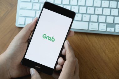 Chiang Mai, Tayland - Mar 28,2018: A Man el kepçe app gösteren Huawei P10 üzerinde ahşap masa üzerinde tutarak. Kapmak smartphone app tabanlı ulaşım ağıdır