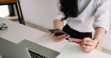 Cep telefonundan alışveriş yapmak ve satın almak için kredi kartı kullanan kadını kapat