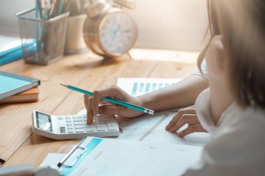 İş adamı ya da muhasebecinin, toplantı odasında iş verilerini ve muhasebe belgelerini hesaplamak için hesap makinesi üzerinde çalışmasını kapat