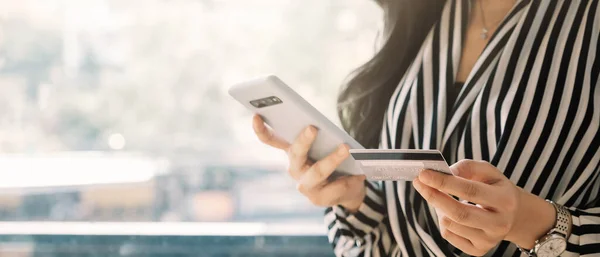 Cerrar mujer sosteniendo teléfono inteligente con tarjeta de crédito para pagar compras en línea e-commerce concepto de pago en línea . — Foto de Stock