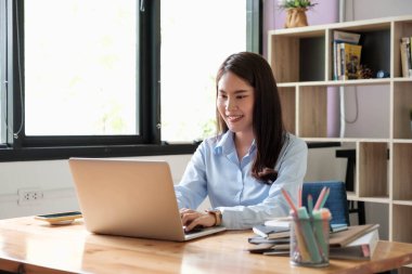 Laptop kullanan genç bir kadının portresi, bir kahve dükkanında dizüstü bilgisayarla çalışıyor.
