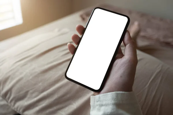 Kvinnlig hand håller smartphone med suddig bokeh. Tomma skärmen mobiltelefon för grafisk display montage — Stockfoto