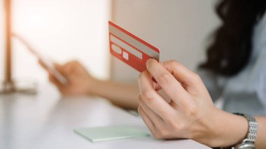 Cep telefonundan alışveriş yapmak ve satın almak için kredi kartı kullanan kadını kapat