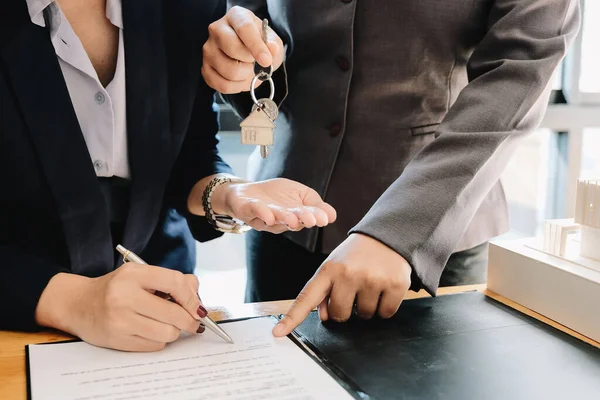 Agente inmobiliario dando llaves de la casa al hombre y firmar un acuerdo en la oficina —  Fotos de Stock