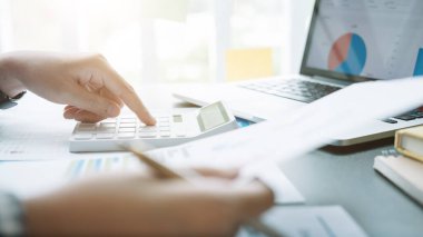 Finans, vergi, muhasebe, istatistik ve analitik araştırma konseptini hesaplamak için hesap makinesi ve dizüstü bilgisayar kullanarak iş adamı ve ortağını kapat