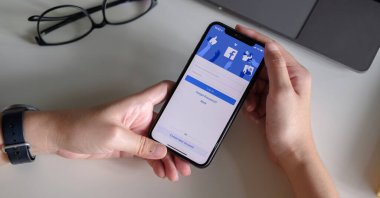 CHIANG MAI, THAILAND - 3 Temmuz 2020: Yeni giriş ekranı ile facebook kullanmak için iPhone X 'i tutan kadın. Facebook dünyanın en büyük sosyal ağı ve en popüler sosyal ağ sitesidir.