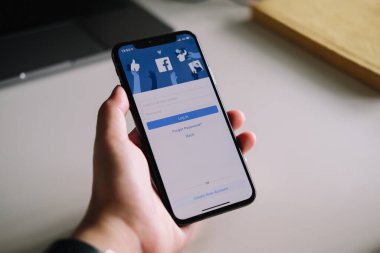 CHIANG MAI, THAILAND - 3 Temmuz 2020: Kadın el ele tutuşması iPhone X, giriş ekranı ile facebook 'u kullanmak için. Facebook dünyadaki en büyük sosyal ağ ve en popüler sosyal ağ sitesidir.