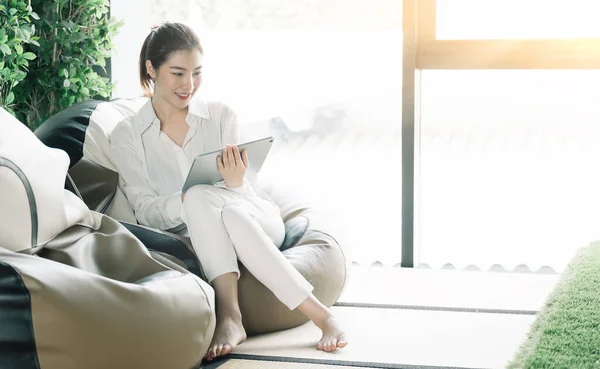 Asian woman usgin smart tablet at home