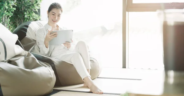 Asian woman usgin smart tablet at home