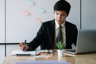 Ofiste finansman için dizüstü bilgisayarla çalışan Asyalı işadamı