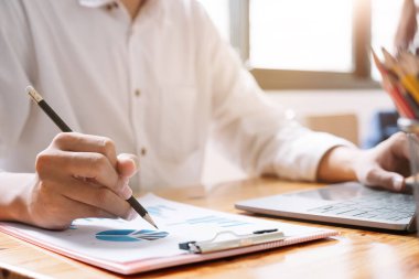 Grafik çizelgesi raporuyla iş adamı kalem değişimi ve veri analizi için dizüstü bilgisayar kullan