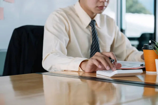 Primer plano del hombre de negocios o contador de mano pluma que sostiene trabajando en la calculadora para calcular los datos comerciales, documento de contabilidad y computadora portátil en la oficina, concepto de negocio —  Fotos de Stock