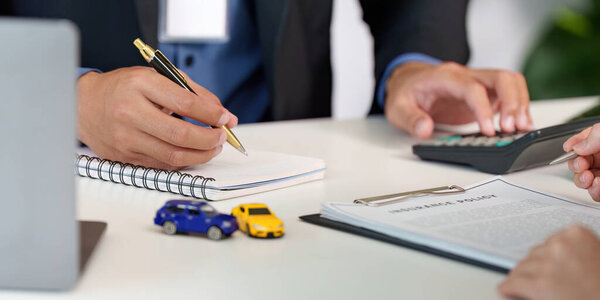 A consultant reviewing a car insurance policy with a client, highlighting key details and options.