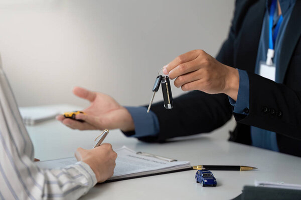 An insurance agent hands over car keys to a client, symbolizing the completion of a transaction during a consultation.