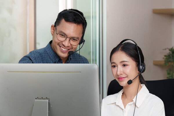 Two call center agents collaborating at a computer, demonstrating effective communication and teamwork in a customer service environment.