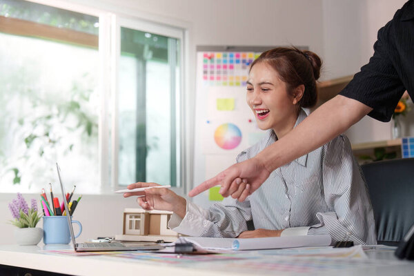 A designer and client engage in a lively discussion about color palettes and design strategies in a bright office.