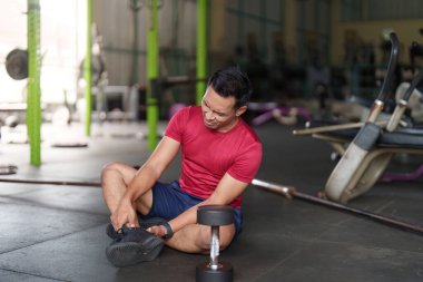 Spor salonunda oturan biri ayak bileğindeki rahatsızlığı hisseder gibi görünür, spor yaparken yaralanma bilincini ön plana çıkarır..