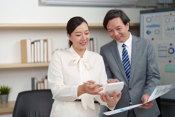 A businesswoman and her colleague review financial data together, emphasizing teamwork and collaboration in the workplace.