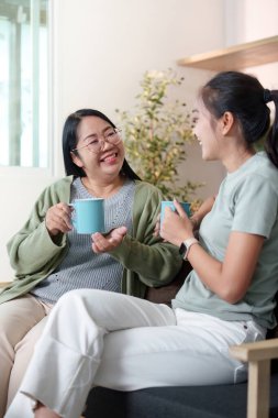 İki kadın çay içerken keyifli bir anı paylaşırken aynı zamanda el işi yapıyor, yaratıcılığını ve bağlantısını sergiliyor..