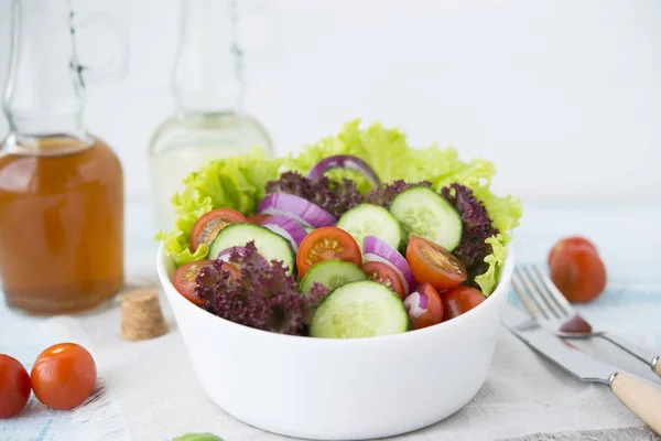 Summer vegetable salad with seasonal vegetables on rustic wooden background.