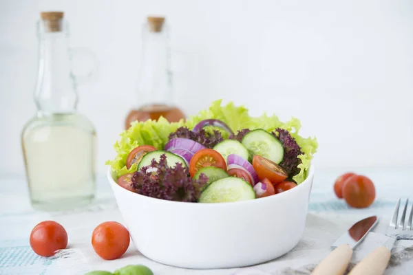 Summer vegetable salad with seasonal vegetables on rustic wooden background.