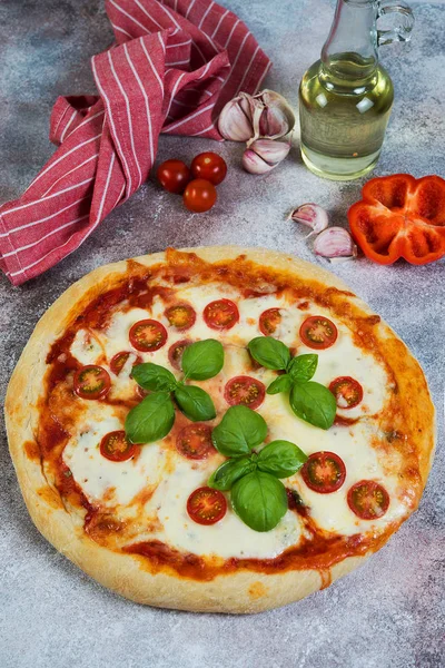 Pizza Margarita with tomatoes and mozzarella cheese on a concrete background.