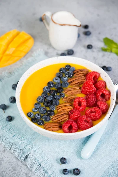 Vegetarian health food. Mango and orange smoothie bowl with fresh berries and nuts.