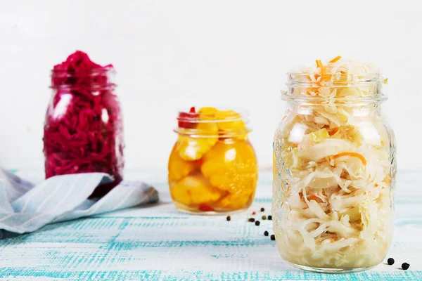 Fermented vegetables in jars. Sauerkraut, pickled beets and pickled squash on a light wooden background. Traditional Russian pickles.