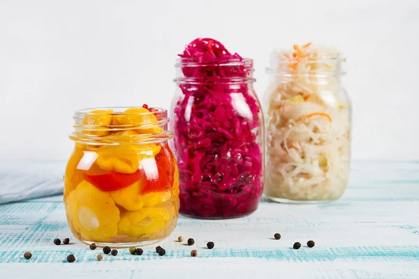 Fermented vegetables in jars. Sauerkraut, pickled beets and pickled squash on a light wooden background. Traditional Russian pickles.
