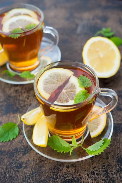 Black hot tea with lemon and mint on wooden background.  Warming autumn revitalizing drink. Vertical orientation. ,