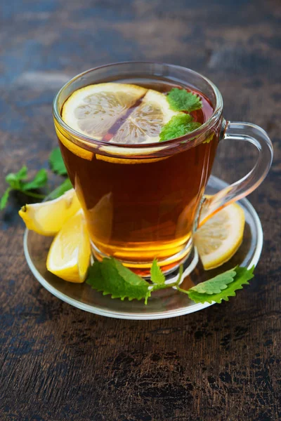 Black hot tea with lemon and mint on wooden background.  Warming autumn revitalizing drink. Vertical orientation. ,